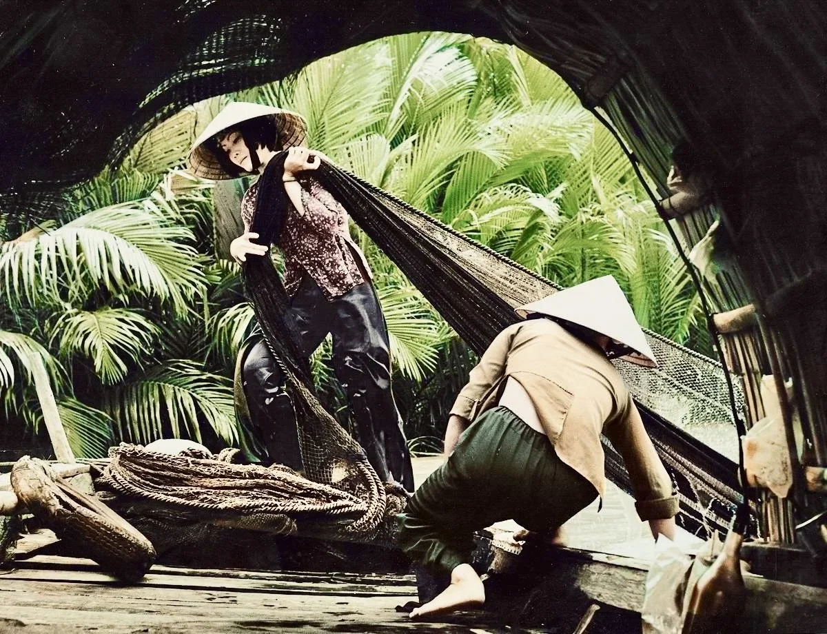 Female fishermen take out nets from the Mekong River. Vietnam, 1974.